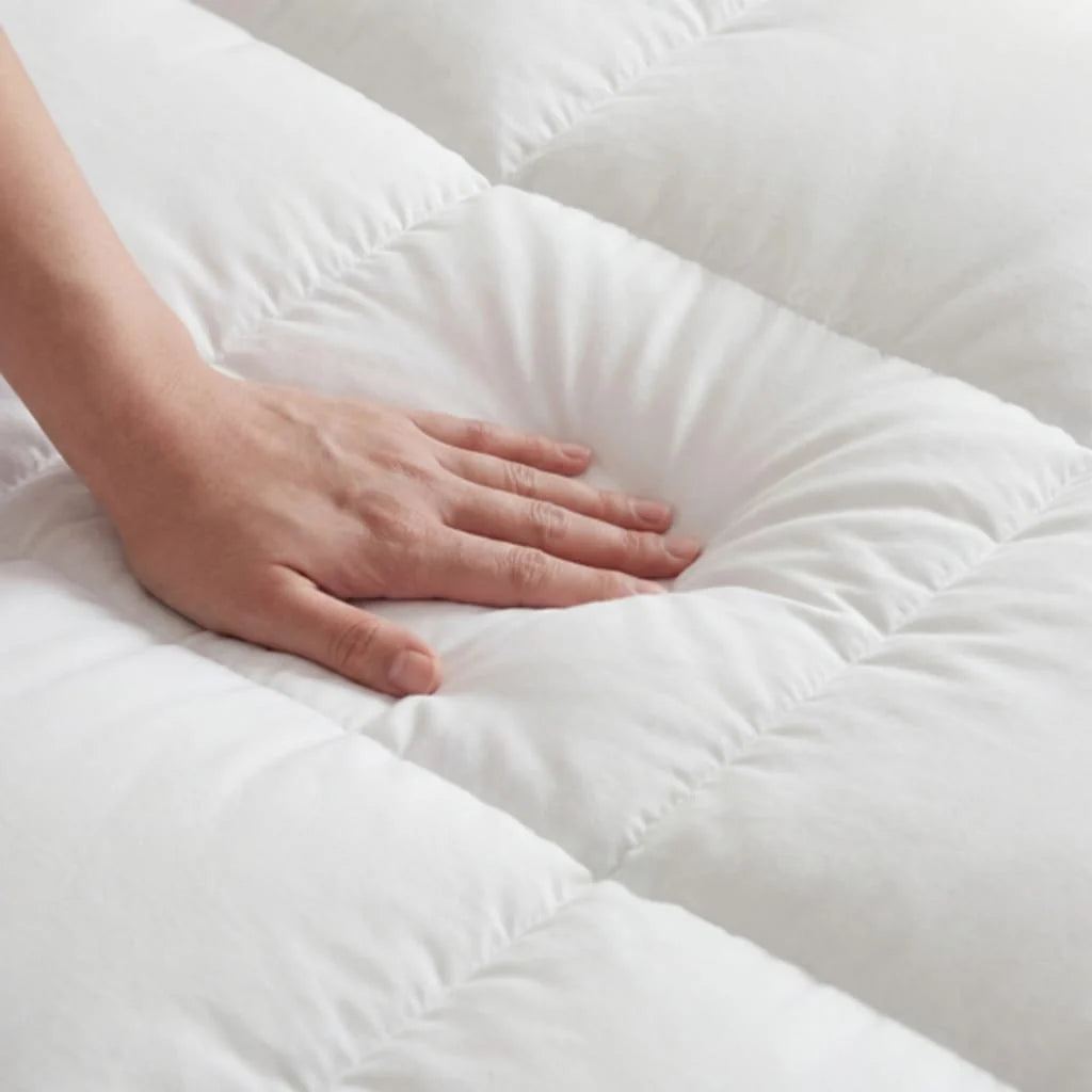 A hand pressing gently into the quilted topper